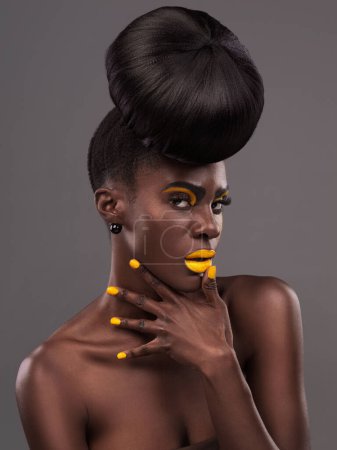 Photo for African, woman and studio color with makeup, beauty and creative yellow lipstick. Bold, model and skin with confidence, dramatic hair and bun for glamour or trendy cosmetics on grey studio background. - Royalty Free Image