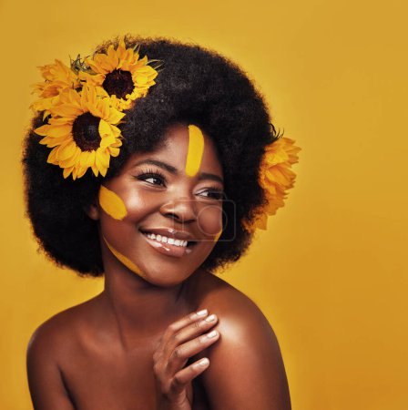 Photo for Black person, beauty and sunflower with skincare in studio for natural glow, cosmetics or soft skin. Woman, plant and confident with smile for organic, dermatology and vitamin e on yellow background. - Royalty Free Image