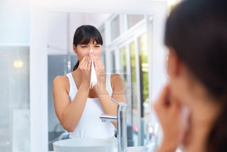 Photo for Asian, woman and allergies in bathroom for healthcare, virus and illness in house for weather change. Sick female person, cough and tissue for sneezing, flu and unhealthy in mirror reflection - Royalty Free Image