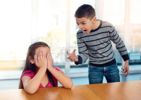 Photo for Scream, siblings and children in argument in home for conflict, bullying or discipline with sadness. Upset, angry and boy shouting at girl for fighting with frustration by table in house together - Royalty Free Image