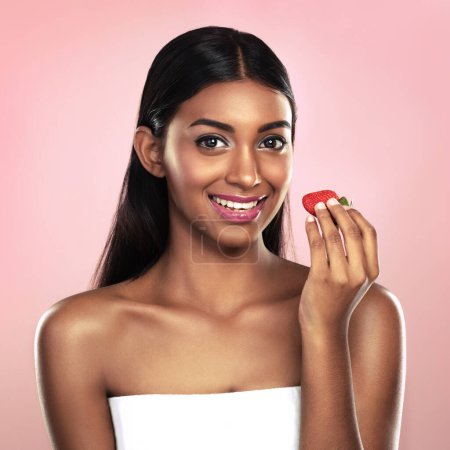 Photo for Portrait, girl or glow of eating, fruit or nutrition, idea or wellness as health on studio mockup. Indian woman, strawberry or smile at planning, weight loss or antioxidant, detox or pink background. - Royalty Free Image