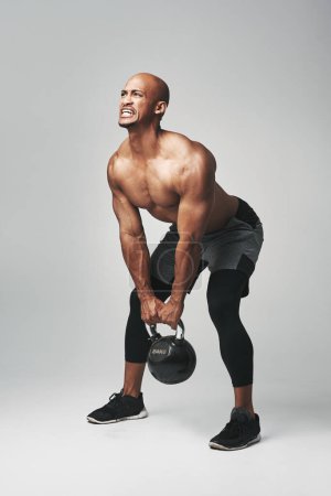 Photo for Black man, heavy and kettle bell in studio, struggle and progress for workout or training. Male person, athlete and commitment to weightlifting on gray background, tough and dumbbell challenge. - Royalty Free Image