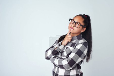 Photo for Thinking, girl and option decision with idea, choice and uncertain with style and fashion in studio. Youth, glasses and mockup space with kid and clever student with pre teen and grey background. - Royalty Free Image