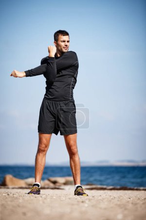 Foto de Hombre, estiramiento y playa para hacer ejercicio con fitness en pose dinámica para la salud con entrenamiento en preparación para correr. Hombre, al aire libre y saludable para el rendimiento con calentamiento para el cuidado del cuerpo. - Imagen libre de derechos
