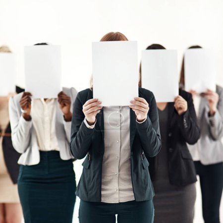 Businesswoman, team and message on blank board in studio for anonymous recruitment of career. Professional, group and female people with empty paper hiding face for marketing as brand ambassador.