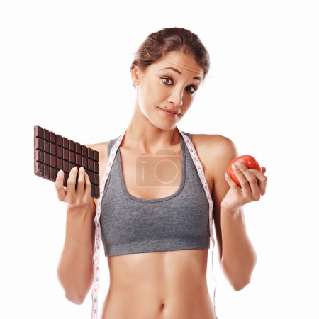Photo for Woman, chocolate and apple with decision and measuring tape for diet, weight loss and balance snacks on white background. Nutrition, fruit and candy, unhealthy versus healthy food with benefits. - Royalty Free Image