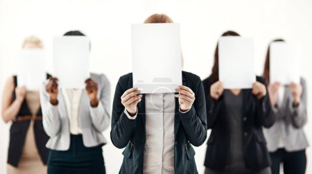 Businesswoman, group and holding message on board in studio for anonymous recruitment of career. Professional, team and female people with blank paper hiding face for marketing as brand ambassador.
