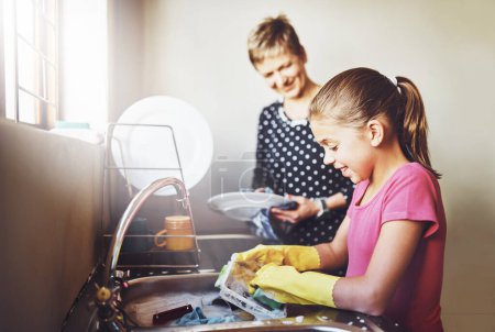 Photo for Kitchen, mother and daughter washing dishes together with help, learning or teaching at basin. Housework, mom and girl in home cleaning at sink with smile, support and morning housekeeping chores. - Royalty Free Image