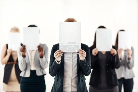 Businesswoman, staff and holding message on board in studio for anonymous interview of career. Professional, group and female people with blank paper hiding face for marketing as brand ambassador.