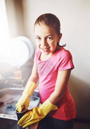Photo for Portrait, washing dishes or child with dirty cup or gloves in kitchen sink in home for healthy hygiene. Happy, development or girl cleaning with soap to disinfect plates of mess, bacteria or germs. - Royalty Free Image