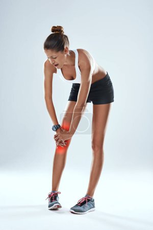 Photo for Sports injury, woman and knee with red glow for fitness, workout and gym in studio holding leg. Acl tear, pain and athlete with weight for training, exercise and medical emergency on gray background. - Royalty Free Image