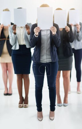 Businesswoman, team and holding message on board in studio for anonymous recruitment of career. Professional, group and female people with blank paper hiding face for marketing as brand ambassador.