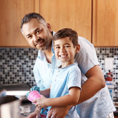 Foto de Niño, retrato y padre lavando platos en la cocina juntos para aprender limpieza en casa. Enseñanza, higiene y papá con niño niño taza de limpieza con paño para las tareas y vinculación en casa - Imagen libre de derechos