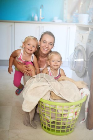 Photo for Mother, kids and portrait of girls, laundry and clothes in basket, washing machine and twins in home. House, woman and mom with babies, growth and development of children, happiness and apartment. - Royalty Free Image