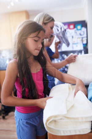 Photo for Children, mother and laundry with towels for chores to learning responsibility at home. Daughter, woman and teamwork with cleaning house by helping, bonding and cooperation together for growth. - Royalty Free Image