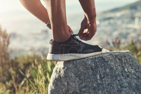 Photo for Runner, foot and tying laces on rock, outdoors and prepare for cardio and marathon training. Man, stone and shoe for exercise or sports in nature, getting ready and sneaker for workout or athlete. - Royalty Free Image