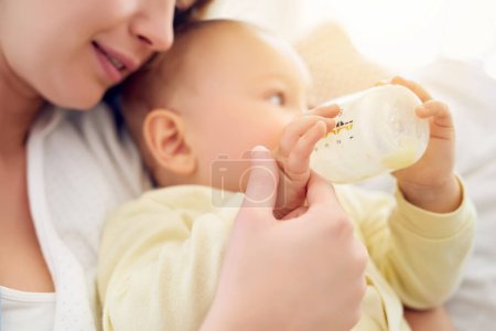 Photo for Mother, formula and baby drinking with bottle for nutrition, growth and childhood development at home. Care, infant and mom with feeding milk in house for love, motherhood and parenting of boy kid. - Royalty Free Image
