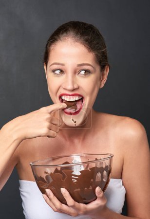 Photo for Woman, chocolate and happiness in studio for cosmetics, baking and sugar for comedy. Candy, pride and cocoa on backdrop for wellness, humour and nutrition isolated on dark background for diet - Royalty Free Image