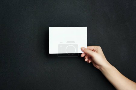 Photo for Hand, studio and blank paper with mockup space for sale, promotion offer or information about us. Closeup, signage or person with placard for news, announcement or logo advertising on dark background. - Royalty Free Image