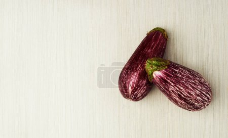 Photo for Eggplant, nutrition and vegan food on table top for wellness, health and diet in studio. Aubergine, green and purple isolated for eating, ingredients and mockup space in house for above and cook - Royalty Free Image