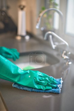 Photo for Hand, glove and kitchen with sink, cleaning and home routine for hygiene and responsibility. Housekeeping, faucet and washing for countertop, polishing and cloth for scrub with domestic housework. - Royalty Free Image