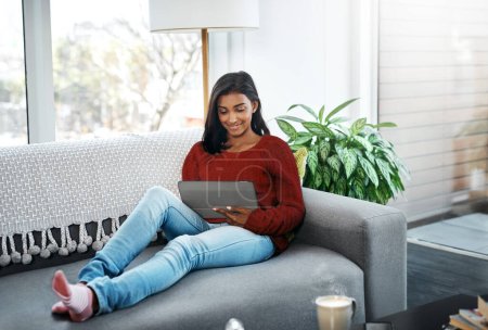 Photo for Relax, home and woman on sofa with tablet for social media, networking or streaming on weekend. Smile, connect and girl on couch with digital app for communication, online chat or search in apartment. - Royalty Free Image