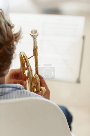 Feuilles, musique et enfant avec trompette pour apprendre, leçon de jazz et pratique pour le spectacle de talent. Musicien, passe-temps créatif et jeune garçon excité avec instrument, papier et maison pour jouer de la chanson ou de la mélodie.