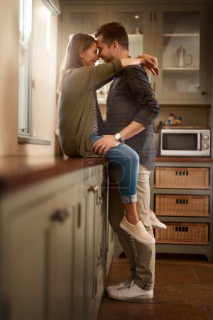 Photo for Love, happy and couple hug in kitchen for bonding, loving relationship and relax together in home. Marriage, morning and man and woman on counter with smile, embrace and affection for commitment. - Royalty Free Image