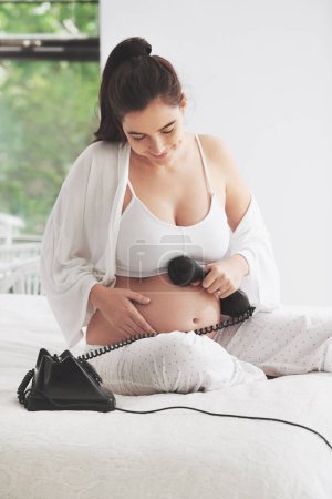 Photo for Pregnant woman, telephone and relax on bed for communication, happiness and contact in bedroom. Mother, smile and conversation in house for care, connection and phone on tummy for voice or sound - Royalty Free Image