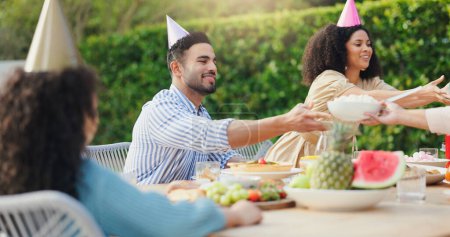 Photo for Family, eating and happy with conversation at birthday party for celebration, surprise or hat in garden of home. Couple, parents and kids with drinks for gathering and event in backyard of house. - Royalty Free Image