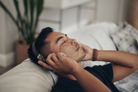 Photo for Home, relax and man with headphones, listening to music and peaceful with wellness and zen. Person, apartment and guy with headset and streaming podcast with break and resting with sound and song. - Royalty Free Image