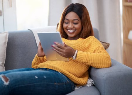 Photo for Tablet, ebook and happy black woman on sofa with social media, reading or website scroll at home. Digital, research or student with streaming app for sign up, online course or elearning registration. - Royalty Free Image