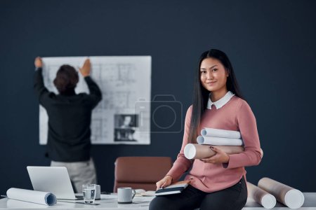 Photo for Architect, woman and smile in portrait with roll of sketch paper, documents and design project. Person, happy and Asian property developer with blueprint for construction, building or job in Jakarta. - Royalty Free Image