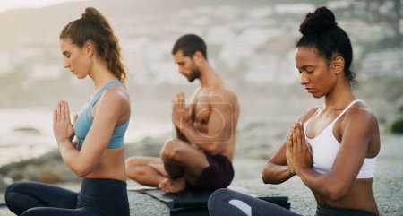 Foto de Hombre, mujeres y meditación en la playa para la paz zen en la niebla de la mañana, mindfulness o curación. Amigos, manos y chakra de bienestar para el autocuidado o yogui holístico como grupo para el equilibrio, la calma o el medio ambiente. - Imagen libre de derechos