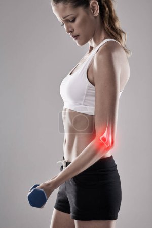 Sports injury, woman and elbow with red glow for fitness, workout and gym in studio. Lateral Epicondylitis, pain and athlete with weight for training, exercise and motivation on gray background.