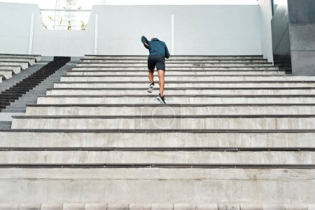 Photo for Running, steps and fitness man at stadium for energy, workout or resilience, training and challenge. Arena, stairs and back of runner with sports, performance or cardio exercise for marathon practice. - Royalty Free Image