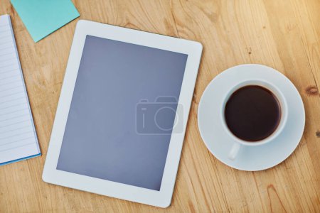 Photo for High angle, table and tablet or coffee in closeup with paper, workspace with technology for background. Notebook, epad and above on desk with drink in zoom, internet or app for marketing business. - Royalty Free Image