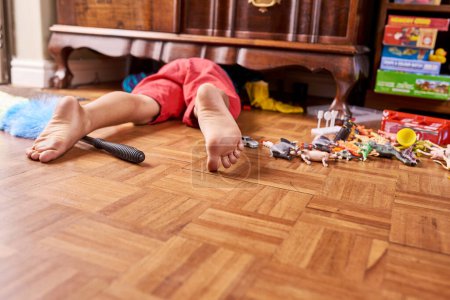 Photo for Child, looking and cupboard on floor in home for lost toy or dust cleaning for chores, playroom or messy. Person, legs and under closet for searching in apartment on ground with feet, youth or tidy. - Royalty Free Image