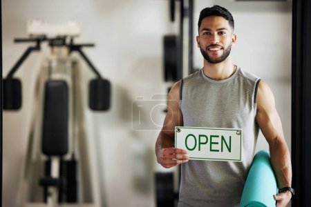 Photo for Man, portrait and open sign in gym for exercise with yoga mat, health workout and startup advertising. Entrepreneur, signage and welcome in wellness club for marketing, sports training and employee. - Royalty Free Image