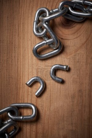 Photo for Freedom, security and broken metal chain for mental health, conflict and power on wood background. Steel, link and divorce from connection, stress and resilience in change, independence or liberation. - Royalty Free Image