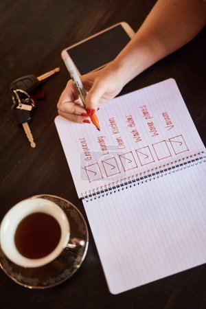 Photo for Person writing, tick or hands with notebook and schedule for daily routine, checklist with coffee. Above, organise and to do list in home with notepad, page and book for planning to write a article. - Royalty Free Image