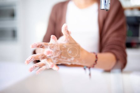 Photo for Person, washing hands and soap with cleaning for hygiene, protect from bacteria or germs with routine or habit at home. Health, wellness and disinfect with foam for fresh scent, safety and skincare. - Royalty Free Image