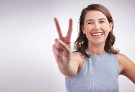 Photo for Portrait, woman and peace sign with smile, feedback and agreement on grey studio background. Face, person or girl with hand gesture, review or emoji with support, wellness or carefree with good vibes. - Royalty Free Image
