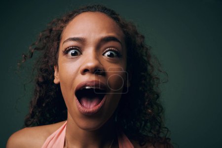 Photo for Face, surprise or alarm with crazy woman, funny or comic with wide eyes on green background. Wild, quirky and playful in portrait for fun, wow with mouth open for reaction or facial expression. - Royalty Free Image