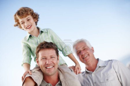 Photo for Portrait of grandfather, father and child by blue sky for bonding, relationship and relax together. Family, generations and grandpa, dad and young boy on shoulders for holiday, vacation and weekend. - Royalty Free Image