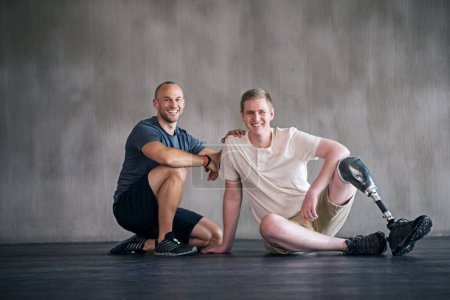 Physiotherapist, person with a disability and prosthetic leg and smile in physiotherapy, studio and gym. Male people, trainer and amputee for wellness, fitness and exercise in sports center.