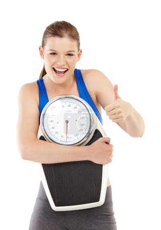 Photo for Portrait of girl, thumbs up and scale for weight loss in studio, measurement and results of fitness goal. Female person, body or care for calories target or achievement, celebrate or white background. - Royalty Free Image
