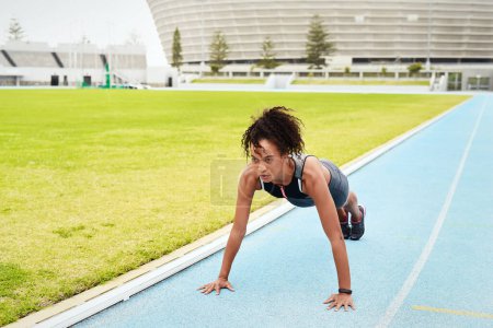 Photo for Woman, athlete and doing push up in stadium for running, training and fitness in summer. Runner, challenge and workout on track field for wellness, cardio and warm up for sports or marathon - Royalty Free Image