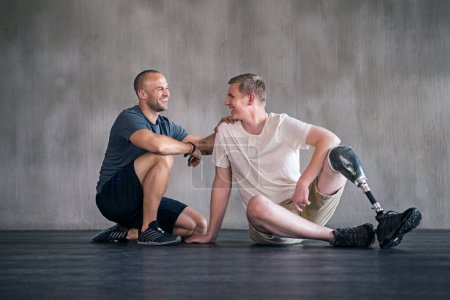 Photo for Physiotherapist, man with a disability and prosthetic leg and laughing in physiotherapy, studio and sportswear. Male people, trainer and amputee fitness for wellness or exercise in sports center. - Royalty Free Image