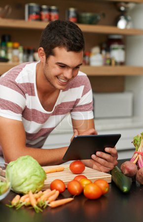 Photo for Online, man and cooking with recipe on tablet in kitchen to watch tutorial video with instructions. Learning, guide and person reading healthy food info on mobile app in home to diet with nutrition. - Royalty Free Image
